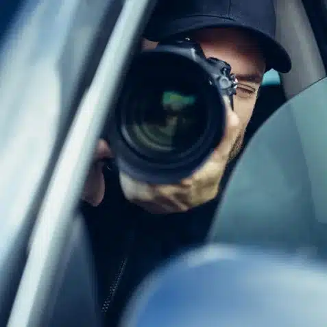 Camera of private investigator in vehicle is taking picture of suspected cheater in phoenix.